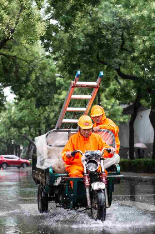 图5：7月12日，两名工人在北京鼓楼西大街冒雨骑行.jpg